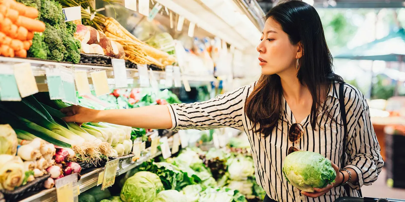 Shopper choosing fresh produce in a grocery store aisle